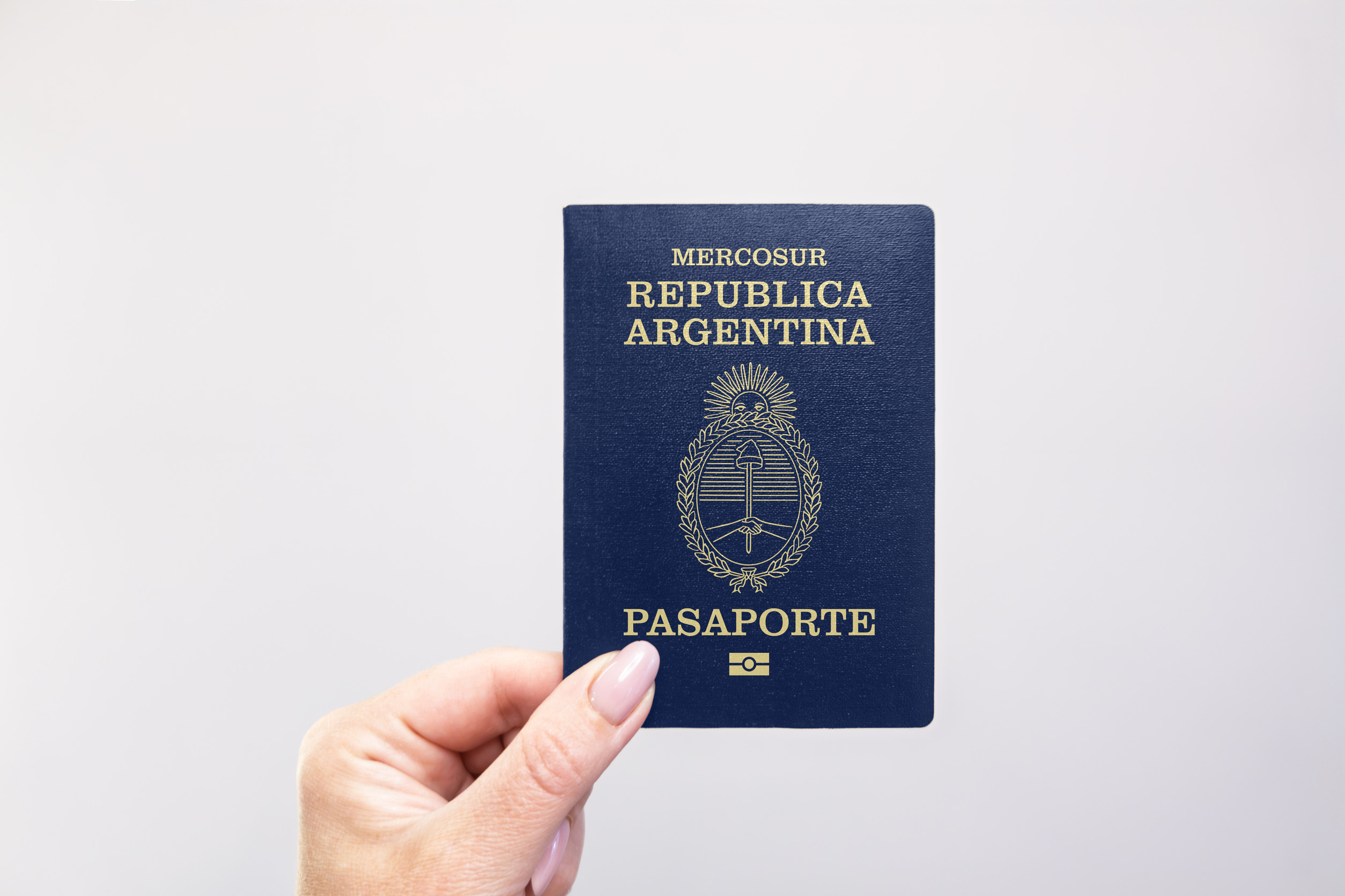 Argentina Held Passport In Hand Against A Plain White Background