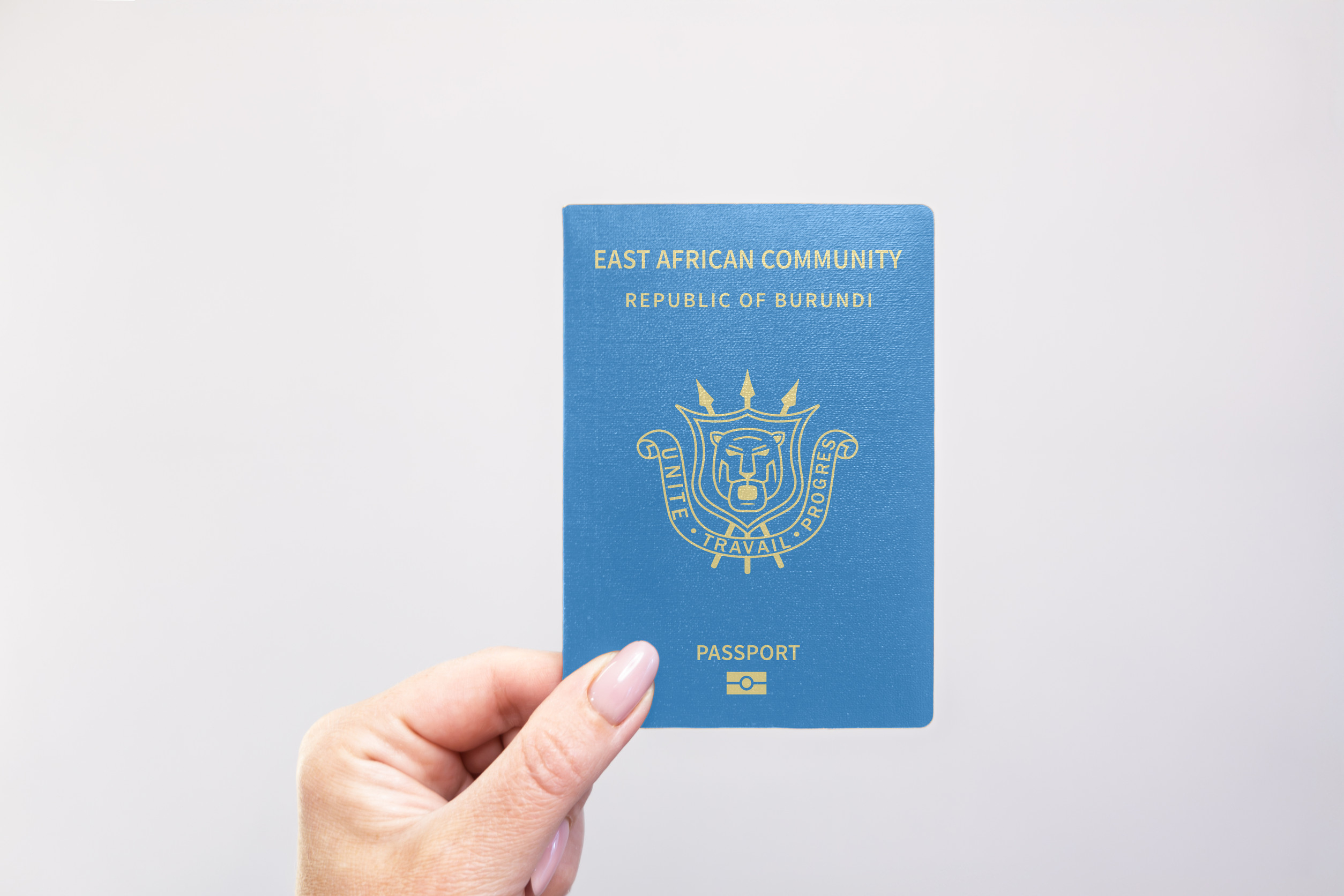 Burundi Passport Held In Hand Against A Plain White Background