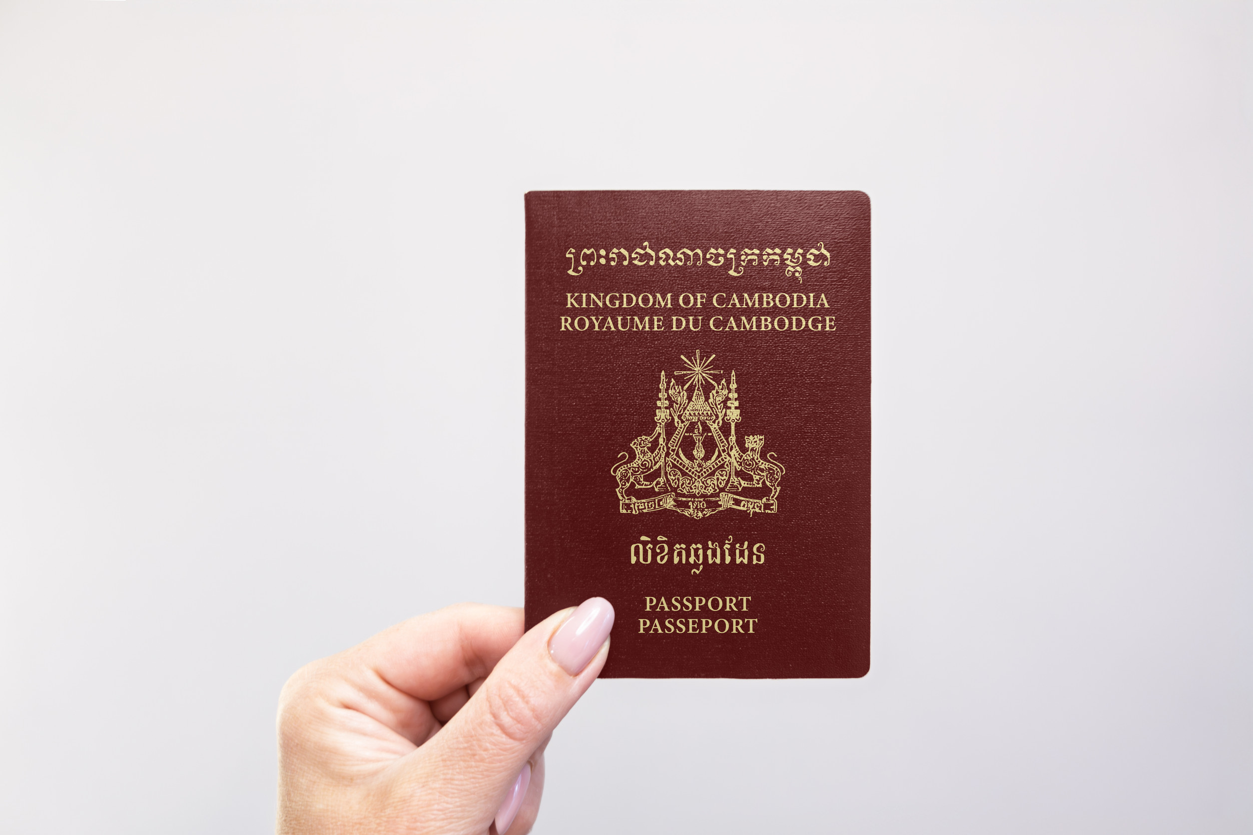 Cambodia Held Passport In Hand Against A Plain White Background