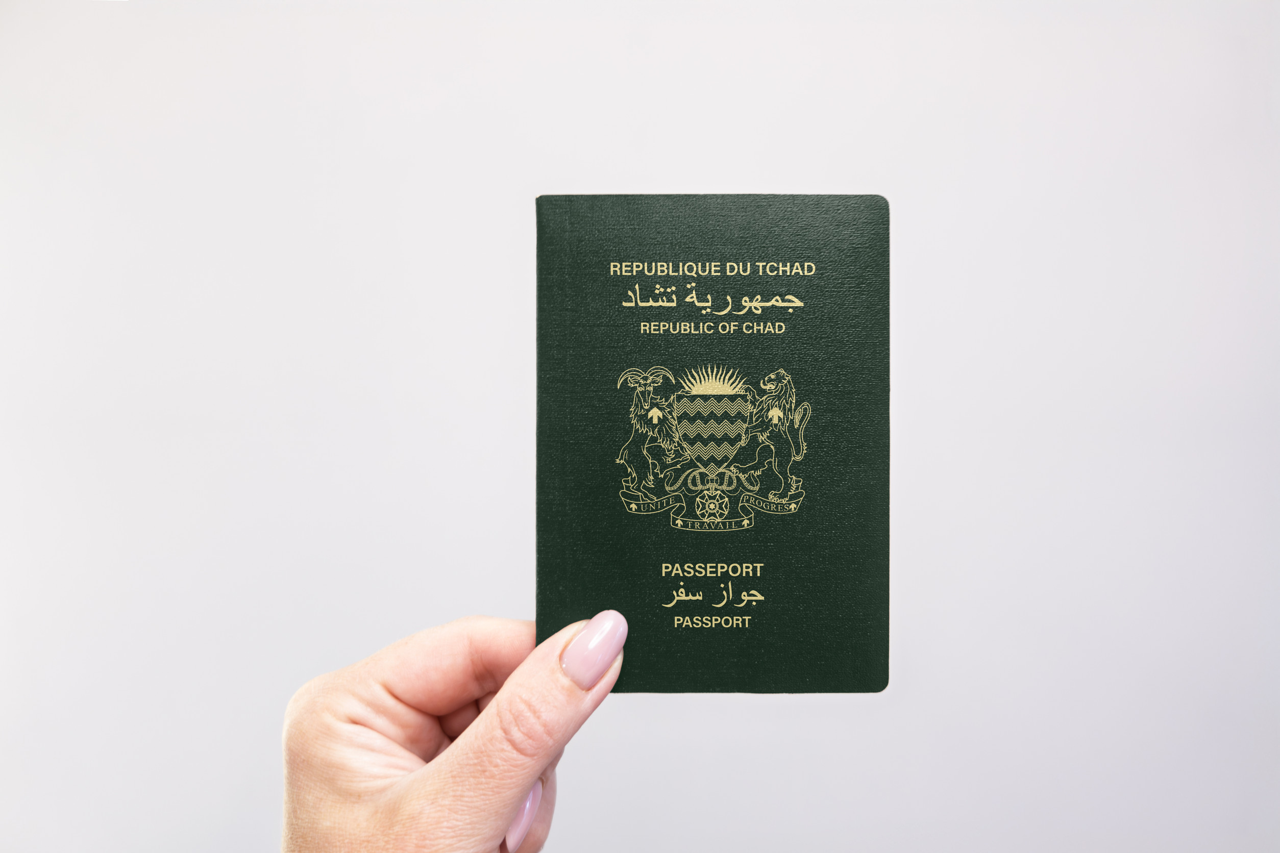 Chad Passport Held In Hand Against A Plain White Background
