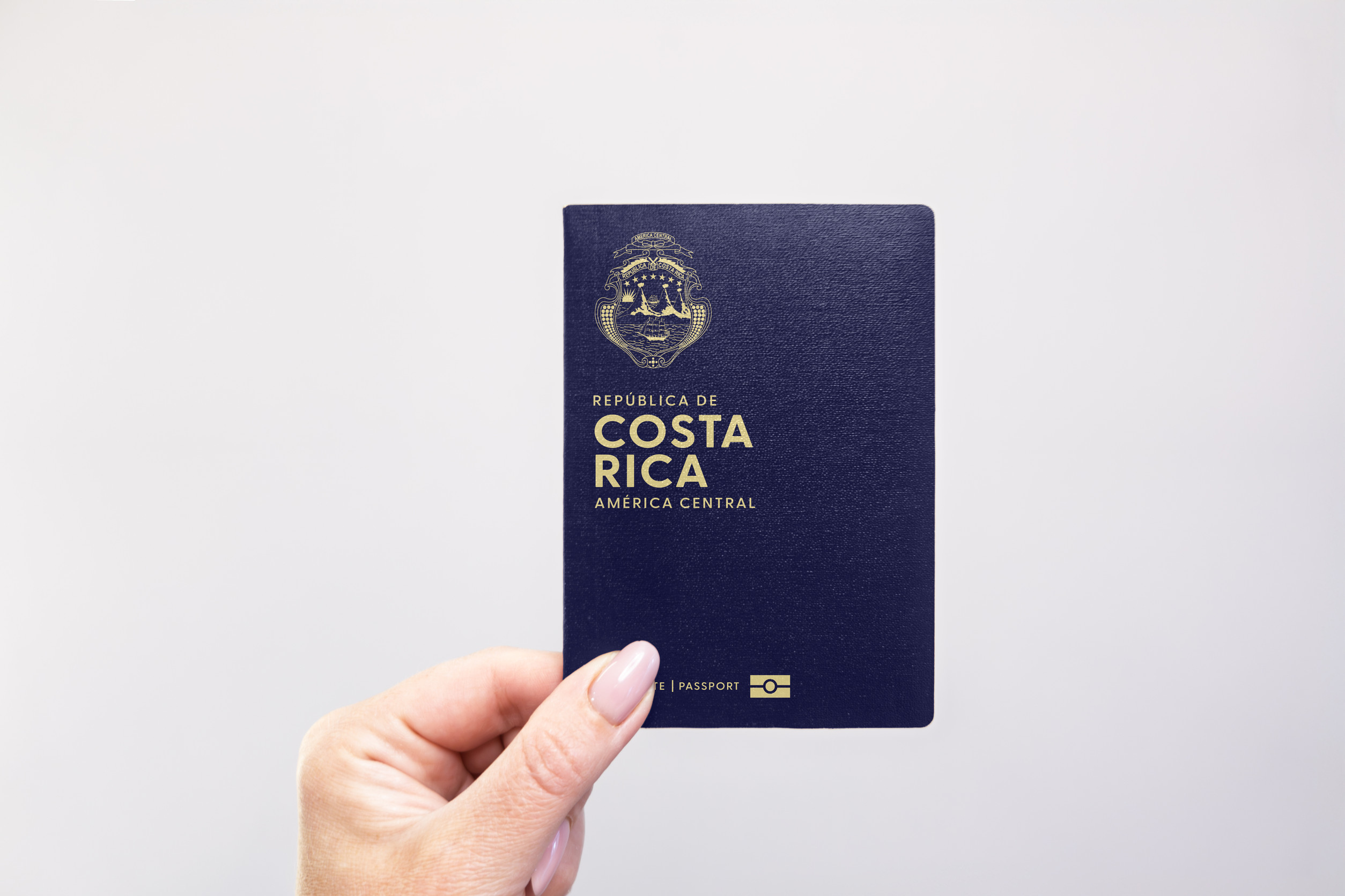 Costa Rica Passport Held In Hand Against A Plain White Background