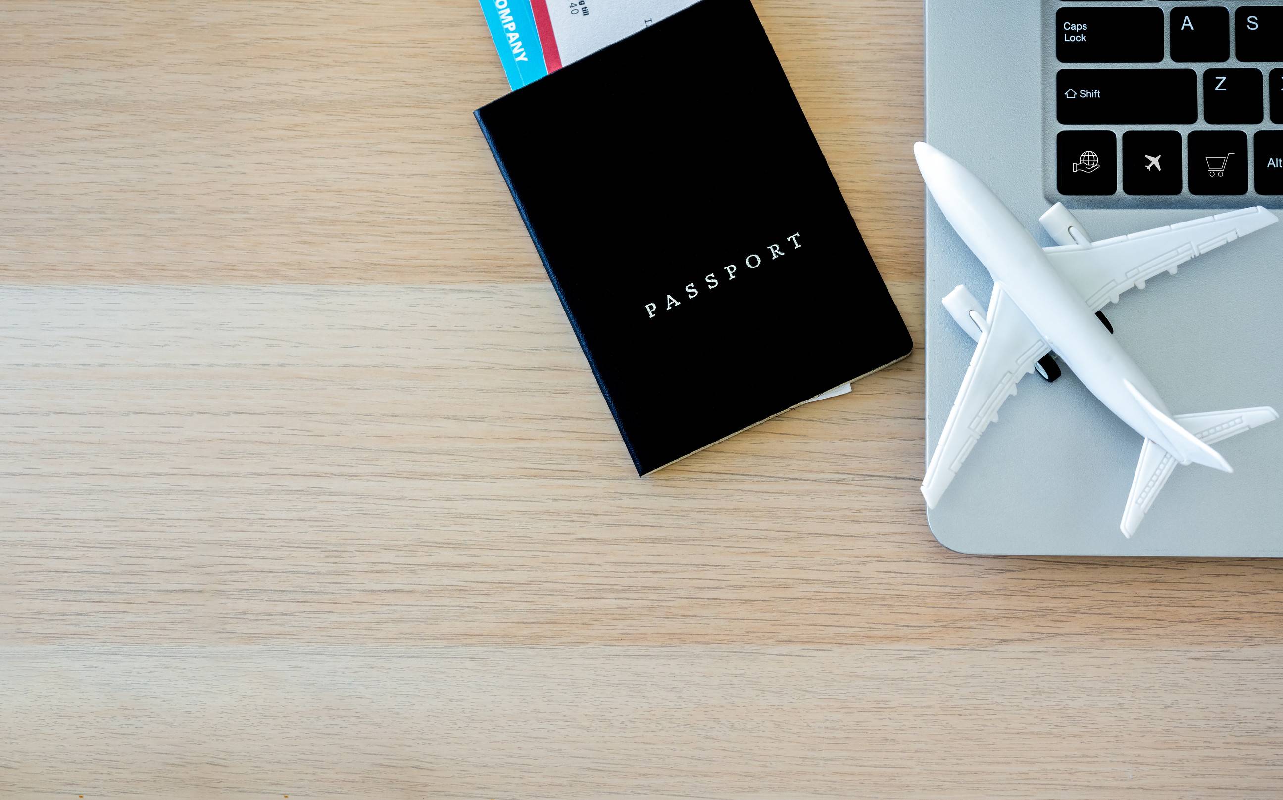 Passport Black Cover With Flight Ticket Near The Laptop